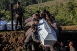 Personil kepolisian memasukkan peti berisi jenazah korban banjir bandang Sentani yang dikuburkan secara massal di Pemakaman Umum Kampung Harapan Sentani, Jayapura, Papua, Rabu (27/3/2019). Sebanyak 20 jenazah yang belum teridentifikasi dikuburkan secara amassal. (ANTARA FOTO)