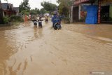 Sejumlah warga melintas di ruas jalan perkampungan yang terendam banjir bandang di Trenggalek, Jawa Timur, Kamis (7/3/2019). Hujan deras selama tujuh jam yang terjadi di wilayah itu pada Rabu (6/3/2019) sore telah menyebabkan Sungai Ngasinan meluap yang memicu banjir bandang dan tanah longsor di lebih dari 15 desa 10 kecamatan. Antata Jatim/Destyan Sujarwoko/zk.