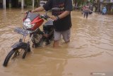 Sejumlah warga melintas di ruas jalan perkampungan yang terendam banjir bandang di Trenggalek, Jawa Timur, Kamis (7/3/2019). Hujan deras selama tujuh jam yang terjadi di wilayah itu pada Rabu (6/3/2019) sore telah menyebabkan Sungai Ngasinan meluap yang memicu banjir bandang dan tanah longsor di lebih dari 15 desa 10 kecamatan. Antara Jatim/Destyan Sujarwoko/zk.