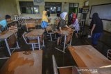 Siswa dan Guru membersihkan lumpur pascterendam banjir di SDN 2 Gunungsari, Sukaratu, Kabupaten Tasikmalaya, Kamis (28/3/2019). Banjir yang diakibatkan tanggul di Sungai Cibanjaran jebol disertai hujan berintensitas tinggi berdampak beberapa jalan, kolam ikan, pesawahan, masjid,dan tujuh rumah warga terendam air banjir. ANTARA JABAR/Adeng Bustomi/agr