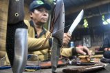 Perajin menunjukkan pisau untuk bertualang di bengkel Afw Knife, Bojong Pesantren, Kelurahan Kertamaya, Kota Bogor, Jawa Barat, Kamis (4/4/2019). Produksi pisau adventure dari bahan baja tools steel dan gagang kayu sonokeling tersebut dalam sebulan mampu menghasilkan 15 pisau custom dan dipasarkan melalui media sosial ke sejumlah daerah di Indonesia hingga mancanegara seperti Malaysia, Brunei Darussalam, Korea, Kanada, Inggris dan Norwegia. (ANTARA FOTO)