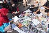 Pengunjung membaca buku secara gratis yang disediakan aktivis literasi di areal Hari Bebas Kendaraan bermotor di Kota Madiun, Jawa Timur, Minggu (7/4/2019). Mahasiswa aktivis literasi menyediakan ratusan buku untuk dibaca secara gratis guna membudayakan membaca kepada masyarakat. Antara Jatim/Siswowidodo/zk.