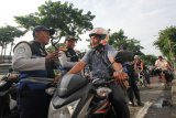 Petugas Dinas Perhubungan Kota Surabaya memberikan imbauan kepada pengendara motor yang kedapatan merokok saat berkendara motor disela sosialisasi pelarangan merokok saat berkendara di Jalan Darmo, Surabaya, Jawa Timur, Selasa (9/4/2019). Kegiatan itu untuk mensosialisasikan Peraturan Menteri Perhubungan Nomor PM 12 Tahun 2019 terkait pelarangan merokok dan menggunakan telepon selular saat berkendara, baik roda empat atau roda dua. ANTARA FOTO/Didik Suhartono/nym.