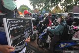 Petugas Dinas Perhubungan Kota Surabaya membentangkan poster berisi himbauan untuk tidak merokok maupun menelpon saat sedang berkendara motor di Jalan Darmo, Surabaya, Jawa Timur, Selasa (9/4/2019). Kegiatan itu untuk mensosialisasikan Peraturan Menteri Perhubungan Nomor PM 12 Tahun 2019 terkait  pelarangan merokok dan menggunakan telepon selular saat berkendara, baik roda empat atau roda dua. Antara Jatim/Didik Suhartono/zk