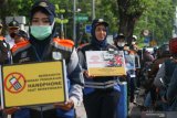 Petugas Dinas Perhubungan Kota Surabaya membentangkan poster berisi himbauan untuk tidak merokok maupun menelpon saat sedang berkendara motor di Jalan Darmo, Surabaya, Jawa Timur, Selasa (9/4/2019). Kegiatan itu untuk mensosialisasikan Peraturan Menteri Perhubungan Nomor PM 12 Tahun 2019 terkait  pelarangan merokok dan menggunakan telepon selular saat berkendara, baik roda empat atau roda dua. Antara Jatim/Didik Suhartono/zk