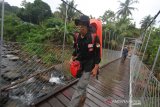 Komisioner KPU Edy Ariansyah melintasi jembatan gantung di Desa Kiyu menuju Desa Juhu untuk memberikan edukasi pemilu terhadap warga Dayak Meratus, di Hulu Sungai Tengah, Kalimantan Selatan, Sabtu (13/4/2019). KPU Kalsel melakukan safari dan pendidikan pemilu kepada warga di sejumlah desa terpencil di kaki pegunungan meratus kalimantan selatan yang hampir 75 persen warganya buta huruf dan sebagai upaya mendorong partisipasi pemilih pada pemilu 2019 di Kalsel. Foto Antaranews Kalsel/Bayu Pratama S.