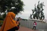 Warga memotret keluarganya dengan latar belakang pembangunan patung Suro dan Boyo di Taman Surabaya, Surabaya, Jawa Timur, Sabtu (13/4/2019).  Pembangunan patung raksasa Suro (hiu) dan Boyo (buaya) di kawasan pesisir Kenjeran tersebut ditargetkan selesai pada bulan Mei 2019 dengan harapan dapat meningkatkan kunjungan wisata dan perekonomian di wilayah setempat. Antara Jatim/Didik Suhartono/zk.