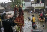 Dalang membawakan kesenian wayang golek di area banjir pada acara Pentas Bandung Lautan Banjir di Bojongasih, Dayeuhkolot, Kabupaten Bandung, Jawa Barat, Minggu (14//4/2019). Kegiatan tersebut merupakan bentuk protes dari warga serta menjadi kegiatan untuk menghibur warga yang telah terdampak banjir sejak hampir sebulan lalu akibat luapan sungai Citarum. ANTARA JABAR/Novrian Arbi/agr.