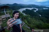 Pengunjung berswafoto dengan latar belakang Waduk Riam Kanan di wisata alam Bukit Matang Kaladan, Banjar, Kalimantan Selatan, Senin (15/4/2019). Pemerintah Provinsi Kalimantan Selatan telah menetapkan program 