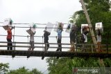 Petugas melewati jembatan gantung saat membawa Logistik Pemilu serentak 2019 menuju desa Atiran,kecamatan Batang Alai Timur, Hulu Sungai Tengah, Kalimantan Selatan, Selasa (16/4/2019).Sebanyak 140 kotak suara, 112 bilik suara, dan 5.292 surat suara di 11 Desa terpencil di Pegunungan Meratus Hulu Sungai Tengah telah didistribusikan KPU Kabupaten Hulu Sungai Tengah.Foto Antaranews Kalsel/Bayu Pratama S.