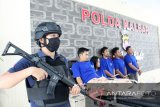 Seorang petugas bersiaga di sebelah lima tersangka penyelundupan narkoba saat rilis ungkap kasus di Mapolda Kalbar, Senin (15/4/2019). Polda Kalbar merilis hasil penangkapan berupa 8,124 kilogram sabu-sabu dan 18.762 butir ekstasi yang diselundupkan dari Malaysia melalui jalur laut yang dilakukan oleh lima anggota sindikat penyelundupan narkoba lintas daerah. ANTARA FOTO/Jessica Helena Wuysang
