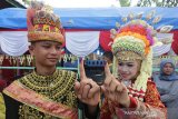 Petugas Kelompok Penyelenggara Pemungutan Suara (KPPS) yang berpakaian adat Aceh memperlihatkan jari yang telah ditandai dengan tinta di Tempat Pemungutan Suara (TPS) Desa Naca, Trumon Tengah, Aceh Selatan, Rabu (17/4/2019). Warga bersama Kelompok Penyelenggara Pemungutan Suara (TPS) menghias TPS dengan nuansa adat Aceh guna menyemarakkan dan meningkatkan partisipasi masyarakat untuk menyukseskan pemilu legislatif dan presiden 2019. (Antara Aceh/Irwansyah Putra)