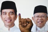 Warga menunjukan jarinya usai memberikan hak suaranya dengan latar poster calon presiden-calon wakil presiden nomor urut 01 Joko Widodo-Ma'ruf Amin di Surabaya, Jawa Timur, Rabu (17/4/2019). Antara Jatim/Zabur Karuru