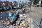 Tumpukan sampah berada di sekitar perahu nelayan yang ditambatkan di Pantai Satelit, Desa Tembokrejo, Muncar, Banyuwangi, Jawa Timur, Jumat (19/4/2019). Pemerintah mengajak semua pihak melakukan aksi pengurangan sampah plastik karena Kementerian Lingkungan Hidup dan Kehutanan RI menyebut produksi sampah plastik di Indonesia mencapai 64 juta ton/tahun dan sebagian besar mencemari lautan, seperti terlihat dari temuan LSM Greenpeace dalam sebuah aksi adanya lebih dari 700 merek sampah plastik di laut. Antara Jatim/Seno/ZK