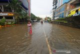 Warga melintasi banjir di kawasan jalan Lambung Mangkurat, Banjarmasin, Kalimantan Selatan, Sabtu (20/4/2019).Banjir yang merendam jalan Kota tersebut masih menjadi masalah rutin yang belum bisa diselesaikan Pemerintah Kota Banjarmasin saat tingginya intensitas curah hujan ditambah tata kelola drainase yang buruk dan masih rendahnya kesadaran masyarakat untuk tidak membuang sampah sembarangan. Foto Antaranews Kalsel/Bayu Pratama S.