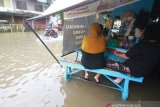 Warga melintasi banjir di kawasan jalan Lambung Mangkurat, Banjarmasin, Kalimantan Selatan, Sabtu (20/4/2019).Banjir yang merendam jalan Kota tersebut masih menjadi masalah rutin yang belum bisa diselesaikan Pemerintah Kota Banjarmasin saat tingginya intensitas curah hujan ditambah tata kelola drainase yang buruk dan masih rendahnya kesadaran masyarakat untuk tidak membuang sampah sembarangan. Foto Antaranews Kalsel/Bayu Pratama S.