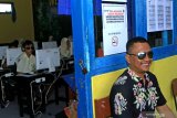 Pelajar berkebutuhan khusus Tuna netra Firdaus Ismail Syah (kiri) didampingi relawan tuna netra Windoyo (kanan) saat mengerjakan soal Ujian Nasional Berbasis komputer (UNBK) di SMP Muhamaddiyah Banyuwangi, Jawa Timur, Rabu (24/4/2019). Firdaus mengerjakan UNBK dengan bantuan aplikasi 