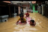 Sejumlah anak bermain air banjir yang merendam kawasan permukiman penduduk Cililitan Kecil, Jakarta, Jumat (26/4/2019). Air kiriman dari bendungan Katulampa tersebut mengakibatkan sejumlah rumah di bantaran Sungai Ciliwung, Jakarta terendam air satu hingga dua meter. ANTARA FOTO/Risky Andrianto/nym