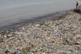 Warga berada di sekitar pantai yang tercemar sampah plastik di pelabuhan Dadap, Indramayu, Jawa Barat, Sabtu (27/4/2019). Pemerintah menargetkan pengurangan sampah plastik di laut pada hingga 70 persen pada tahun 2025. ANTARA JABAR/Dedhez Anggara/agr
