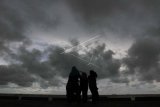 Sejumlah warga berada di kawasan pantai yang di selimuti mendung hitam di Desa Suak Indrapuri, Johan Pahlawan, Aceh Barat, Jumat (26/4/2019). Badan Meteorologi Klimatologi dan Geofisika (BMKG) stasiun Meteorologi Nagan Raya mengimbau masyarakat nelayan dan wisatawan untuk berhati-hati karena cuaca ekstrem yang datang secara tiba-tiba seperti angin kencang dan hujan deras disertai petir di kawasan pantai barat selatan Aceh. (ANTARA FOTO/Syifa Yulinnas/pd)