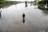 Warga melintas di Jalan Raya yang terendam banjir di Porong, Sidoarjo, Jawa Timur, Senin (29/4/2019). Banjir yang diakibatkan curah hujan tinggi sejak Minggu (28/4) malam tersebut mengakibatkan jalan raya Porong terendam air setinggi 60 cm. Antara Jatim/Umarul Faruq/zk.