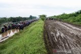 Sejumlah pengendara sepeda motor melewati tanggul penahan lumpur Lapindo untuk menghindari banjir di Porong, Sidoarjo, Jawa Timur, Senin (29/4/2019). Pengendara sepeda motor tersebut tidak bisa melewati jalan raya Porong yang terendam air setinggi 60 cm akibat curah hujan yang tinggi sejak Minggu (28/4) malam. Antara Jatim/Umarul Faruq/zk.