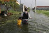 Warga menerobos banjir di kawasan Kelurahan Sumberejo, Kecamatan Pakal, Surabaya, Jawa Timur, Jumat (3/5/2019). Banjir yang menggenangi pemukiman di kawasan itu akibat jebolnya tanggul Kali Lamong pada jumat (3/5/2019) dini hari. Antara Jatim/Didik Suhartono/zk.