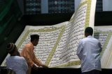 Pengeblat membalik Al Quran Raksasa saat bertadarus di Masjid Baiturrahman, Banyuwangi, Jawa Timur, Selasa (7/5/2019). Al Quran raksasa yang ditulis tangan oleh Abdul Karim memiliki ukuran halaman 142 x 210 centimeter, mulai ditulis pada 1 Februari 2010 dan selesai pada 26 Agustus 2010 untuk dibaca setiap bulan Ramadan di Masjid Baiturrahman Banyuwangi. ANTARA FOTO/Budi Candra Setya/pd.