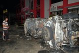 Warga melihat bangkai mobil yang rusak dampak kerusuhan di Lapas Narkotika Kelas III Langkat, di Langkat, Sumatera Utara, Kamis (16/5/2019). Akibat peristiwa kerusuhan yang dilakukan para narapidana di Lapas tersebut mengakibatkan tiga mobil dan dua sepeda motor petugas rusak terbakar dan ratusan napi melarikan diri. ANTARA FOTO