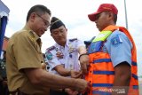 Wali Kota Pontianak Edi Rusdi Kamtono (kiri) bersama Kepala Kantor Syahbandar dan Otoritas Pelabuhan (KSOP) Kelas II Pontianak Capt Bintang Novi (tengah) memasangkan rompi pelampung (life vest) kepada petugas pelabuhan saat apel pembukaan posko angkutan laut lebaran tahun 2019 di Pelabuhan Dwikora Pontianak, Kalimantan Barat, Senin (20/5/2019). Posko angkutan laut di Pelabuhan Dwikora yang dibuat KSOP Kelas II Pontianak dan turut melibatkan 23 instansi yaitu antara lain Basarnas, Custom Imigrasi Karantina, TNI AL, Kepolisian, serta Pelindo tersebut bertujuan untuk memberikan rasa aman dan nyaman bagi penumpang transportasi laut. ANTARA FOTO/Jessica Helena Wuysang