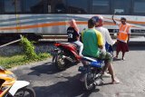 Relawan memberi isyarat kepada pengendara ketika ada Kereta Api (KA) melintas di perlintasan rel Kereta Api (KA) tanpa palang pintu di Kabupaten Madiun, Jawa Timur, Jumat (24/5/2019). Beberapa warga di sekitar perlintasan tersebut secara bergantian menjaga perlintasan rel KA tanpa palang pintu guna mengantisipasi terjadinya kecelakaan, dengan menerima imbalan dari pengendara secara sukarela. Antara Jatim/Siswowidodo/zk.