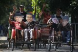 Warga menaiki becak sambil menggunakan penutup wajah bergambar pasangan capres cawapres peserta Pemilu 2019, Joko Widodo- Ma'ruf Amin dan Prabowo Subianto -Sandiaga Uno saat aksi damai di Solo, Jawa Tengah, Jumat (24/5/2019). Dalam aksi tersebut mereka berharap capres nomor urut 01 Joko Widodo dan capres nomor urut 02 Prabowo Subianto segera bertemu guna rekonsiliasi pascapilpres 2019. ANTARA FOTO