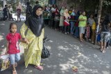 Warga berjalan di dekat antrean usai menerima zakat fitrah di kawasan Sekeloa, Bandung, Jawa Barat, Selasa (4/6/2019). Sedikitnya 500 paket zakat fitrah yang dikumpulkan dari sejumlah keluarga dan warga kawasan tersebut dibagikan langsung kepada masyarakat yang membutuhkan jelang hari raya idulfitri 1440 Hijriah. ANTARA JABAR/Novrian Arbi/agr