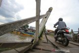 Pengendara melintas di jembatan yang berbahan kayu ulin di Kuin Banjarmasin,Kalimantan Selatan, Jumat (7/6/2019).Kondisi jembatan berbahan kayu ulin yang menghubungkan Kuin Utara dan Kuin Selatan tersebut sangat memprihatinkan.Foto Antaranews Kalsel/Bayu Pratama S.