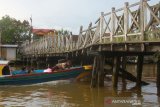 perahu bermesin (kelotok) melintas di bawah jembatan yang berbahan kayu ulin di Kuin Banjarmasin,Kalimantan Selatan, Jumat (7/6/2019).Kondisi jembatan berbahan kayu ulin yang menghubungkan Kuin Utara dan Kuin Selatan tersebut sangat memprihatinkan.Foto Antaranews Kalsel/Bayu Pratama S.