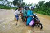 Warga membantu mendorong pengendara motor melintasi jalan poros pulau laut yang terendam banjir di Desa Sungup Kanan, Kabupaten Kotabaru, Kalimantan Selatan,Sabtu (8/6/2019).Hujan deras yang mengguyur Kabupaten Kotabaru selama tiga hari terakhir membuat air sungai meluap dan mengakibatkan akses jalan utama untuk menuju Kotabaru terendam banjir.Foto Antaranews Kalsel/Bayu Pratama S.