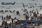 Nelayan berlayar mengatarkan sejumlah wisatawan menggunakan perahunya di Pantai Pangandaran, Jawa Barat, Minggu (9/6/2019). Sejumlah Nelayan di Pangadaran beralih profesi menjadi jasa angkutan perahu wisatawan saat musim libur Lebaran untuk mengantar wisatawan yang berkunjung ke Pantai Pasir Putih dengan tarif Rp 20.000 per orang. ANTARA JABAR/Adeng Bustomi/agr