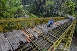 Pengendara motor melintasi Jembatan Bailey Gobang yang rusak di Kampung Gobang, Kota Tasikmalaya, Jawa Barat, Jumat (14/6/2019). Jembatan Bailey Gobang yang menghubungkan Kota Tasikmalaya dengan Kabupaten Tasikmalaya serta Kabupaten Ciamis tersebut rusak dan tidak layak dilintasi kendaraan, sehingga membahayakan warga yang melintas. ANTARA JABAR/Adeng Bustomi/agr