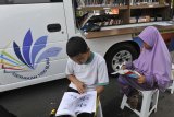 Dua anak membaca buku dari mobil perpustakaan keliling yang dihadirkan di arena Car Free Day (CFD) di Alun-alun Kota Serang, Banten, Minggu (23/6/2019). Untuk mengembangkan minat baca generasi muda Pemda setempat mencanangkan gerakan Literasi 1000 Buku dengan mengerahkan sejumlah mobil perpustakaan keliling ke tempat keramaian dan ke pelosok perkampungan. ANTARA FOTO/Asep Fathulrahman/SB/