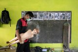 Seorang siswa membawa manekin melintasi gambar rancangan robot polisi berbahan onderdil motor bekas di SMK Karya Utama, Warung Bambu, Karawang, Jawa Barat, Senin (24/6/2019). Robot tersebut menggambarkan polisi menggendong anak kecil yang diciptakan oleh siswa jurusan teknik perawatan mekanik industri untuk hadiah pada HUT Bhayangkara ke - 73. ANTARA JABAR/M Ibnu Chazar/agr