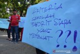 Para orang tua yang anaknya tidak diterima masuk SMP negeri menggelar aksi protes di SMPNi 1 Jombang, Jawa Timur, Rabu (26/6/2019). Mereka menuntut agar Mendikbud mengevaluasi sistem PPDB zonasi yang dianggap tidak fair, terutama soal perhitungan jarak yang tidak sesuai dengan ketentuan karena banyak siswa rumahnya tidak lebih dari 1 km dari sekolah tersebut tidak lolos. Antara Jatim/Syaiful Arif/zk