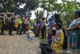 Warga dibantu anggota Polisi dan TNI mengisi air bersih gratis yang didistribusikan dari Polres Tasikmalaya Kota menggunakan mobil water cannon berisi 6.000 liter air di Desa Cijualang, Kabupaten Tasikmalaya, Jawa Barat, Kamis (27/6/2019). Sejak dua bulan lalu, daerah tersebut mengalami krisis air bersih karena dampak dari terjadinya kekeringan akibat dilanda musim kemarau, sehingga warga harus mengambil air bersih dengan jarak tempuh dua kilometer. ANTARA JABAR/Adeng Bustomi/agr