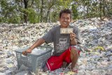 Warga menunjukan temuan uang dolar Amerika saat memilah sampah plastik di tumpukan sampah impor di Desa Tamansari, Karawang, Jawa Barat, Senin (1/7/2019). Berdasarkan data dari Lembaga Kajian Ekologi Dan Konservasi Lahan Basah Ecoton, sebanyak 10.800 ton kebutuhan 