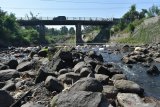 Pengendara melintasi jembatan Sungai Jeroan, Kabupaten Madiun, Jawa Timur, Selasa (2/7/2019). Akibat musim kemarau Sungai Jeroan yang pada musim penghujan lalu meluap hingga merendam sejumlah wilayah selama beberapa hari itu saat ini mulai kering dan tinggal menyisakan sedikit air serta tumpukan sampah. Antara Jatim/Siswowidodo/zk.