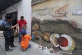 Warga etnis Tionghoa dan pribumi melihat seniman Aceh melukis mural di gampong keberagaman, Peunayong, Banda Aceh, Kamis (4/7/2019). Komunitas mural yang melibatkan seniman membuat mural tentang sejarah Aceh, keberagaman, tolak narkoba dan kampanye kebersihan di 32 lokasi di kawasan pasar tradisonal peunayong. (Antara Aceh / Irwansyah Putra)
