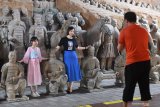 Pengunjung berfoto di samping patung prajurit di Museum Prajurit Terakota di Xi'an, Shaanxi, China, Jumat (5/7/2019). Pada hari libur kunjungan wsatawan ke lokasi tersebut mencapai sedikitnya 90 ribu pengunjung tiap harinya dan rencananya akan ada pembatasan jumlah kunjungan ke objek wisata itu. Antara Jatim/Zabur Karuru