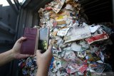 Awak media memotret kertas bekas (waste paper) impor yang dikirim dari Australia di lapangan penumpukkan kontainer di PT Terminal Petikemas Surabaya (TPS) di Surabaya, Jawa Timur, Selasa (9/7/2019). Kantor Pengawasan dan Pelayanan Bea dan Cukai (KPPBC) Tipe Madya Pabean (TMP) Tanjung Perak Surabaya mengamankan delapan kontainer yang berisi 282 bal dengan berat total 210,34 ton kertas bekas (waste paper) yang terkontaminasi berbagai sampah rumah tangga dan terkontaminasi limbah Bahan Berbahaya dan Beracun (B3). Antara Jatim/Didik Suhartono/ZK