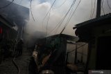 Petugas memadamkan kebakaran di permukiman padat penduduk di kawasan Margorukun, Surabaya, Jawa Timur, Rabu (10/7/2019). Sekitar 15 unit kendaraan pemadam kebakaran dikerahkan untuk memadamkan api yang membakar sekitar 14 rumah itu. Antara Jatim/Didik Suhartono/ZK