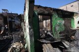 Petugas melakukan proses pembasahan pada sejumlah rumah yang terbakar di permukiman padat penduduk di kawasan Margorukun, Surabaya, Jawa Timur, Rabu (10/7/2019). Sekitar 15 unit kendaraan pemadam kebakaran dikerahkan untuk memadamkan api yang membakar sekitar 14 rumah itu. Antara Jatim/Didik Suhartono/ZK
