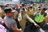 Polisi dan Satpol PP menenangkan sejumlah kepala desa yang berunjuk rasa menuntut diselenggarakannya pemilihan kepala desa (pilkades) serentak di kantor Pemkab Kediri, Jawa Timur, Rabu (10/7/2019). Sedikitnya 200 kepala desa berunjuk rasa menuntut segera diselenggarakannya pilkades serentak di 250 desa agar tidak terjadi kekosongan jabatan yang pada akhirnya hanya akan diisi oleh pejabat sementara dari unsur aparatur sipil negara (PNS) yang tidak sesuai dengan pilihan masyarakat. Antara Jatim/Prasetia Fauzani/zk.